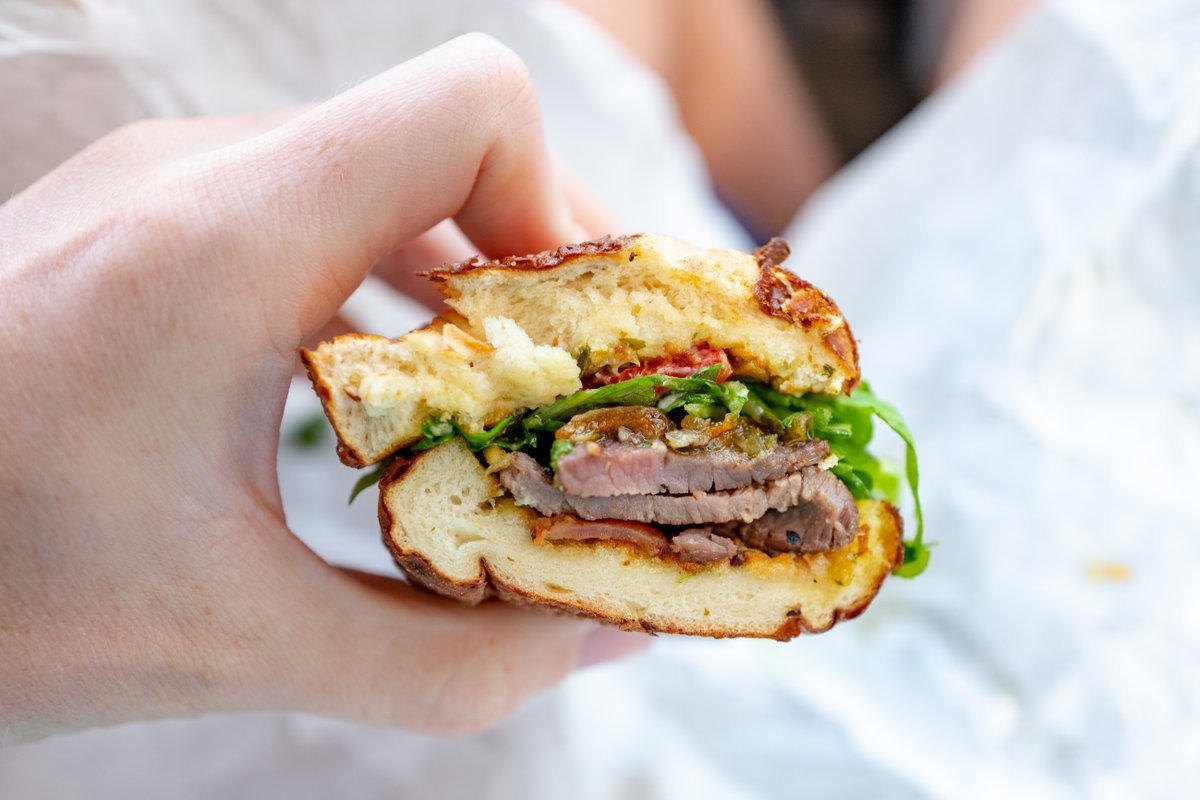 Photograph of Mendocino Farms, a restaurant in San Ramon, California, United States, close-up of hand of man holding sandwich