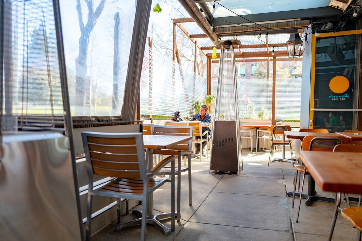Photograph of a customer sitting at the table in the enclosed patio with a heater, at the Parada Kitchen Peruvian Restaurant in Walnut Creek, California, February, 2021.